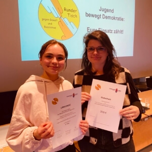 Studierende und Kunstlehrerin halten Auszeichnungsurkunden in den Händen